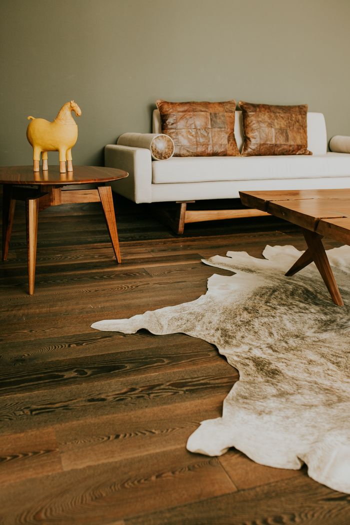A stylish living room featuring mid-century modern furniture, leather accents, and a decorative rug.